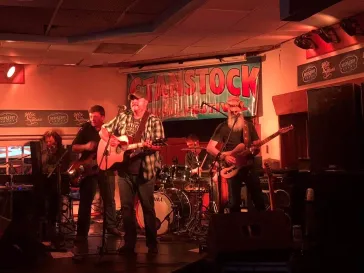 Full band performing at Woodstock venue under warm stage lights