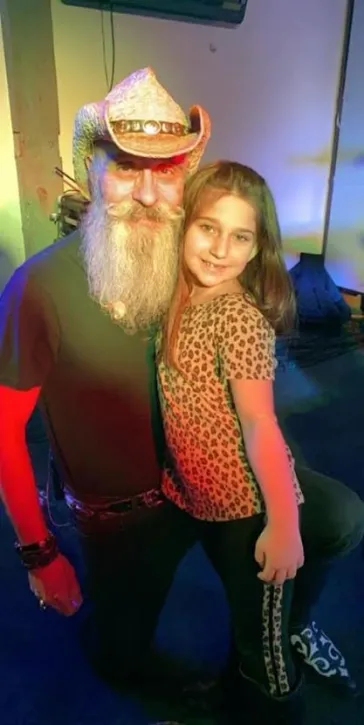 Dino posing with a young fan under colorful stage lights