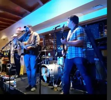 Mark and Tom performing on stage with blue ambient lighting