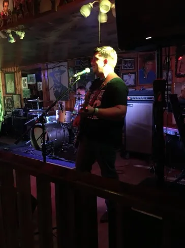 Mark performing on stage at a dimly lit venue