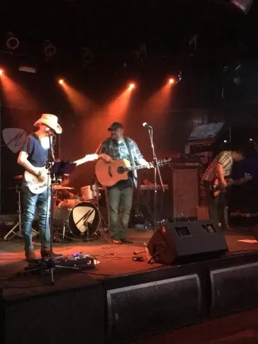 Full band performing on stage under warm stage lights