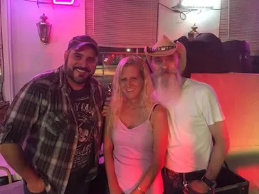 Three people posing together under pink neon lighting