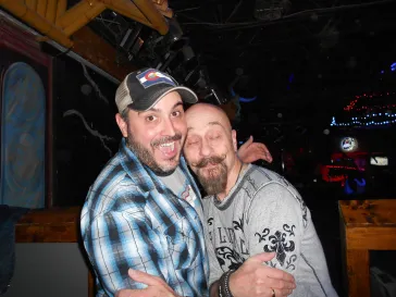 Two friends posing together and smiling at an indoor bar