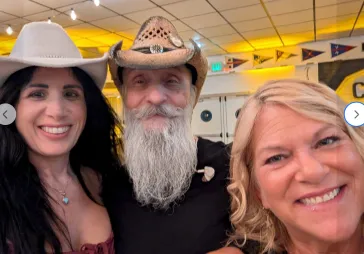 Three fans with cowboy hats at a show