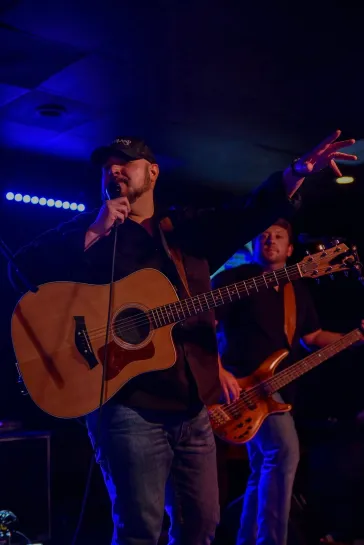 Mark singing with guitarist and bassist on stage