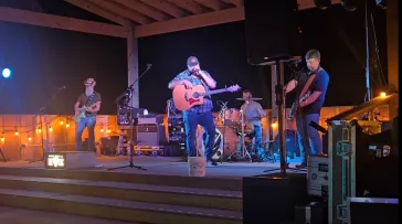Full band performing on outdoor stage at night