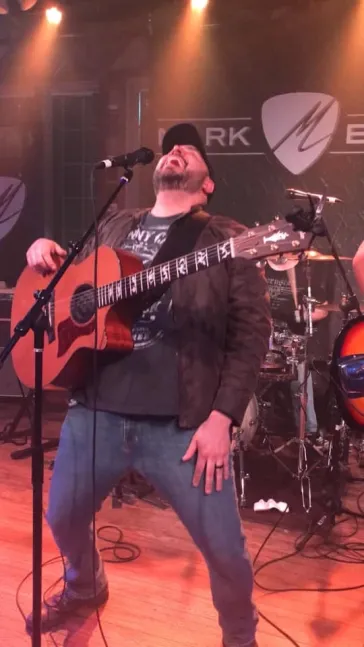 Mark Bray performing with acoustic guitar at Mark Bray venue