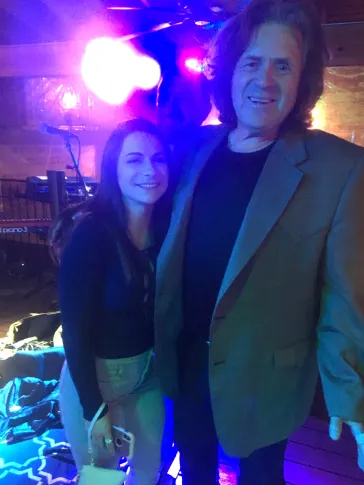 Two people posing with purple stage lighting