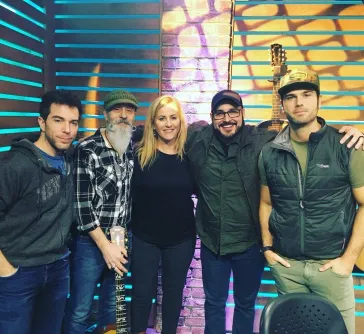 Band and friends posing in front of colorful neon backdrop