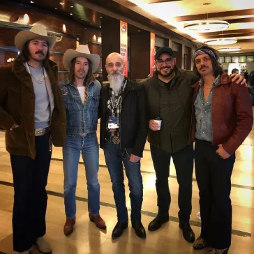 Five band members posing together in a hotel lobby