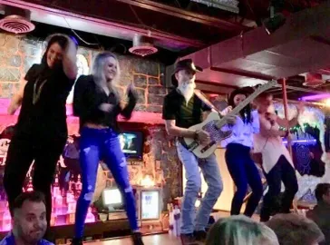 Fans dancing on stage with the band at a packed show