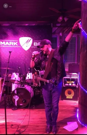 Mark performing at the Mark Bray venue under pink neon lights